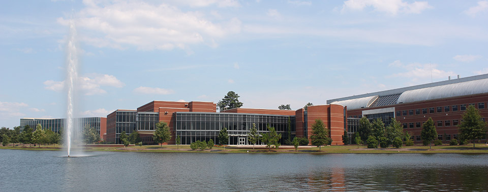 An image of the MGA campus with a pond in the foreground